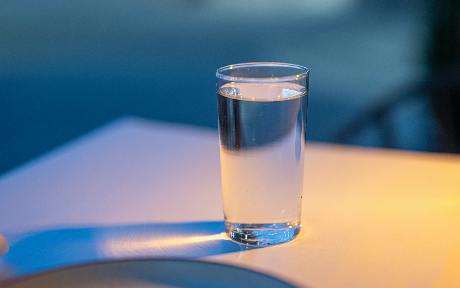 Un vaso de agua sobre una mesa, con luz cálida de tarde