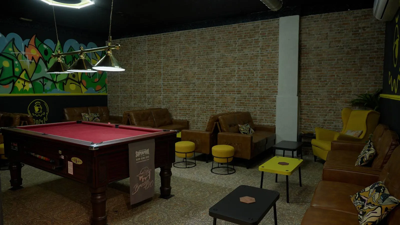 Zona de descanso con pared de ladrillo y mesa de billar