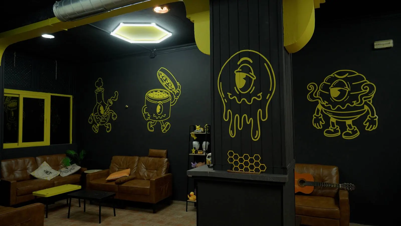 Zona lounge con sofás de piel y mascotas pintadas en pared negra
